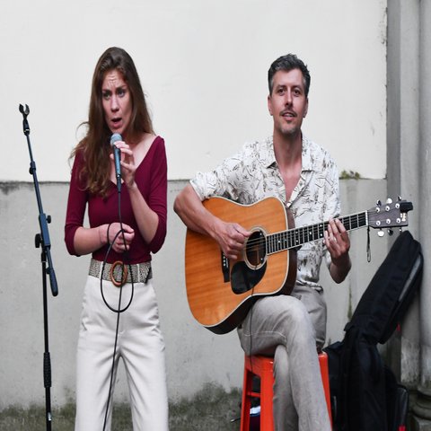 Eine Frau singt und ein Mann spielt Gitarre