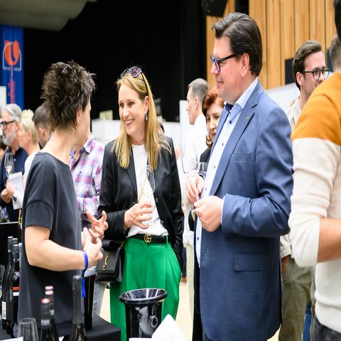 Drei Personen in einer Konversation, sie haben ein Glas Wein in der Hand