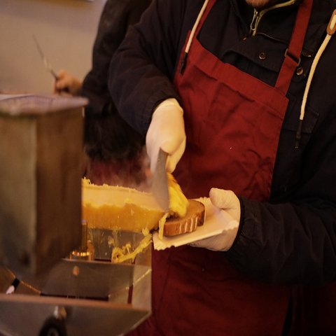 Eine Person schiebt Käse auf eine Brotscheibe