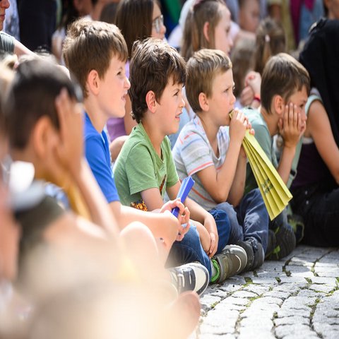 Kinder sitzen auf dem Boden und schauen ganz gespannt