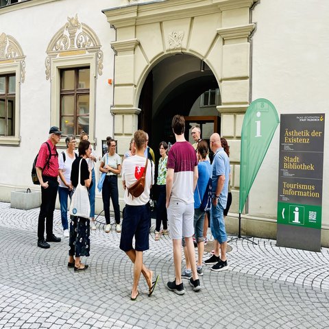 Eine Gruppe von Menschen steht vor einem Gebäudeeingang