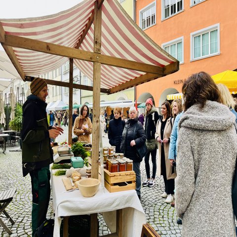 Eine Menschengruppe an einem Marktstand in einer Stadt