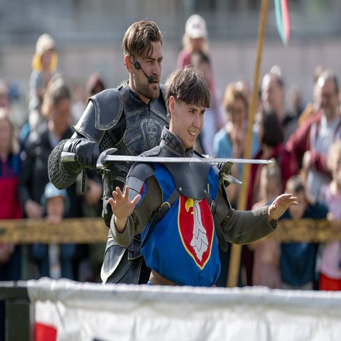 Ein Mann steht mit einem Schwert hinter einem jungen Mann