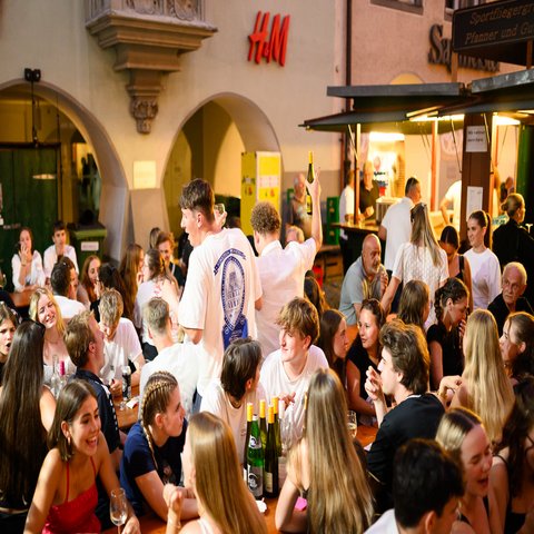 Viele Menschen sitzen an Bierbänken und feiern