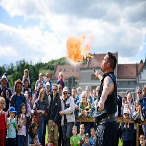 Ein Feuerspucker, im Hintergrund sein Publikum