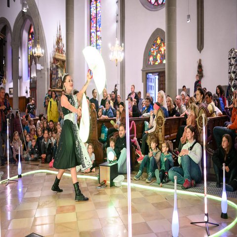 Eine Straßenkünstlerin tritt in einer Kirche auf