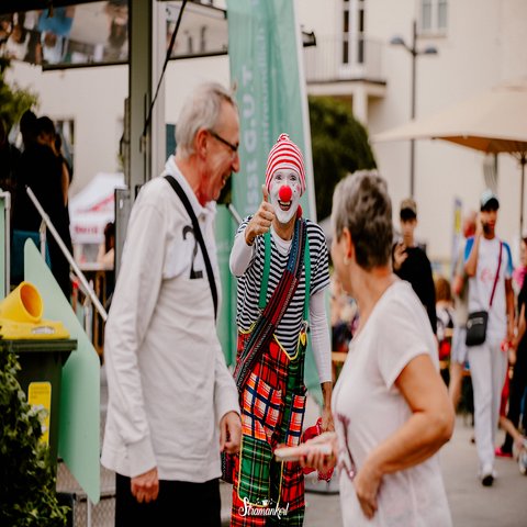 Ein Clown bringt zwei ältere Menschen zum Lachen