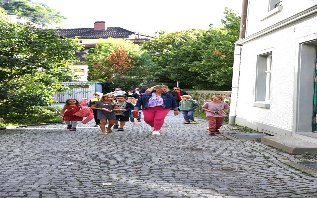 Eine Gruppe von Kindern, ganz vorne läuft eine Frau