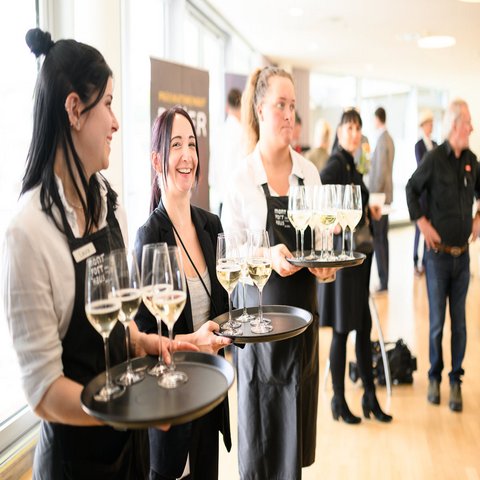 Drei Frauen mit Tabletts und Weingläser