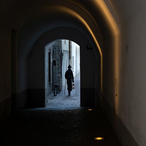 Ein Nachtwächter läuft durch Lauben einer Stadt