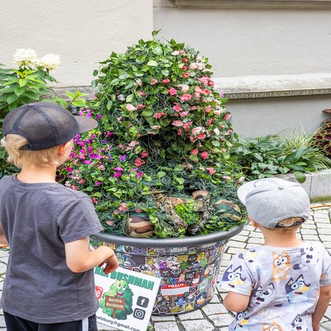 Austria Bushman sitzt da, zwei Kinder schauen ihn an