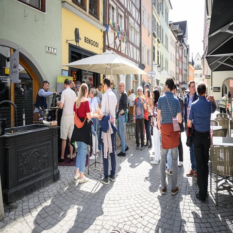 Mehrere Menschen stehen in der Gasse einer Stadt