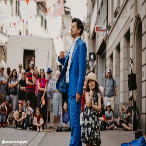 Ein Mann im blauen Anzug steht vor seinem Publikum
