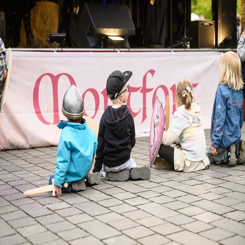 Kinder sitzen vor einer Bühne