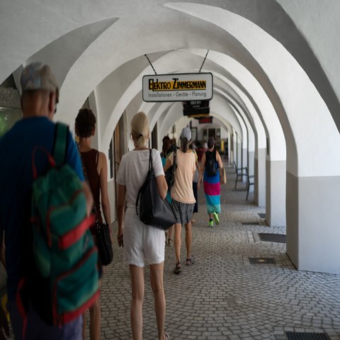 Menschen laufen unter den Lauben von alten Gebäuden