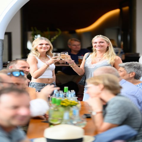 Zwei junge Frauen stoßen mit einem Glas Wein an