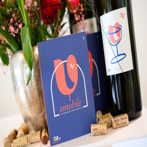 Ein Buch, mehrere Korken, eine Weinflasche und ein Blumenstrauß stehen auf einem Tisch