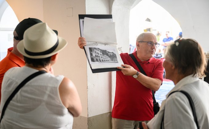 Ein Mann zeigt ein altes Bild eines Gebäudes aus seiner Mappe